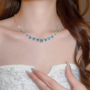 Close-up of model wearing an elegant necklace with a blue gemstone and silver chain