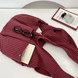 Detail view of burgundy plaid tote bag with front snap pocket and textured fabric finish