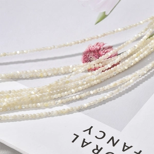 Macro view of 2-2.5mm natural white shell beads strand on a minimalist magazine background