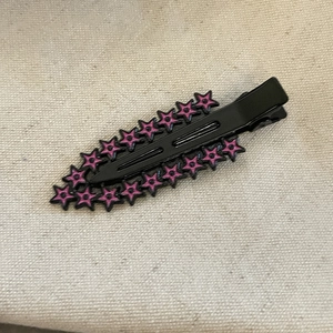 Détail d'une pince à cheveux punk avec étoiles roses sur finition en métal noir