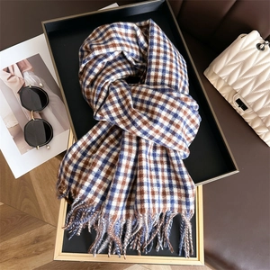 Detail of soft blue and brown checkered scarf with tassels on a stylish black tray