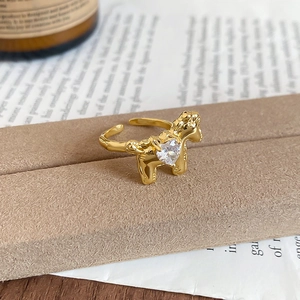 Detailed view of adjustable golden pony ring with heart zircon on vintage jewelry stand