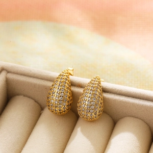 Close-up of teardrop stud earrings with micro-paved zircons in a beige velvet jewelry box