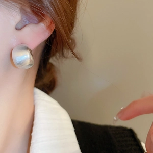 Close-up of minimalist silver geometric C-shape earrings with brushed matte finish