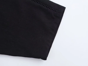 Close-up of black linen shirt sleeve with detailed hollow-out stitching and fine texture