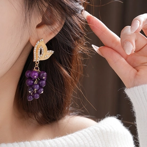 Close-up of French vintage grape earrings with purple beads and gold leaf details