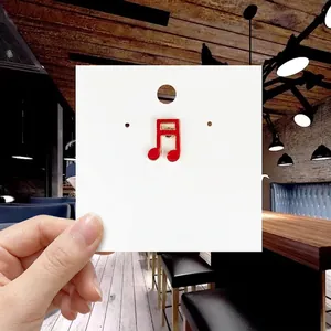 Detail of red enamel musical note brooch with gold trim on white display card
