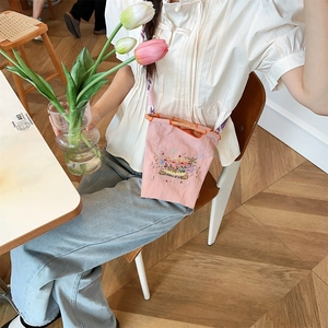 Close-up of pink oxford canvas bag with carousel embroidery and woven handles