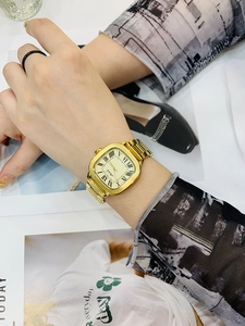 Close-up of elegant gold rectangular watch with Roman numerals on a model wrist