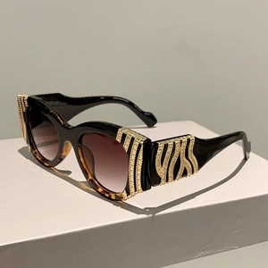 Detail view of black vintage sunglasses with leopard print and wavy gold metal trim