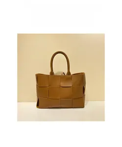 Macro shot of brown wide-woven leather tote bag with thick strap handle and polished finish