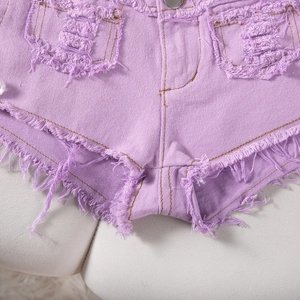 Dettaglio ravvicinato di shorts in denim viola con orli sfrangiati e strappi in stile distressed