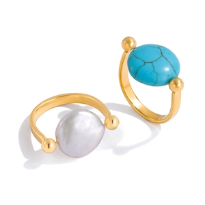 Detailed shot of golden rings featuring a blue turquoise stone and a white baroque pearl