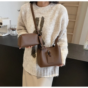 Detail of a brown lychee-textured bucket bag set styled with a beige sweater