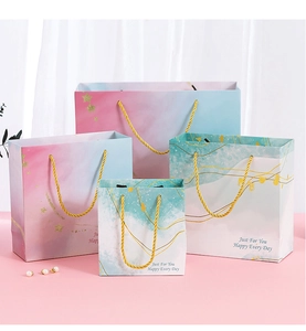 Detailed view of pink and blue gradient gift bags with elegant gold braided handles