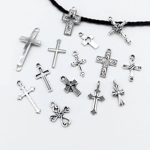 Verscheidenheid aan zilveren vintage kruishangers en een zwarte koordketting op witte basis