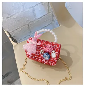 Detail of red tweed girl's bag with pearl handle and cute bunny doll charm accessory