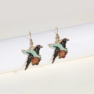 Close-up of raven and red rose earrings with Solitude text on blue ribbon detail