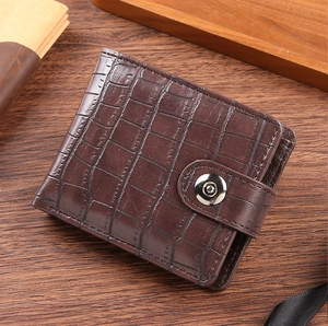 Detail of dark brown crocodile pattern wallet with snap closure on a wooden desk