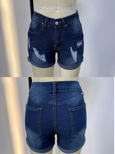 Detail of ripped denim shorts in dark blue with distressed texture and rolled hems