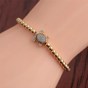 Adjustable turtle bracelet in gold finish with blue and red cubic zirconia accents