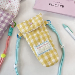 Detailed close-up of quilted yellow checkered camera bag with pink heart buckle and blue strap