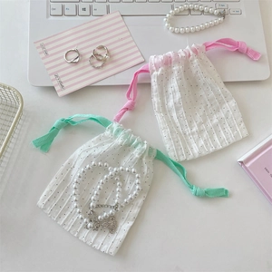 Detalle de bolsas para joyas de lunares con cordón y elegantes accesorios de perlas