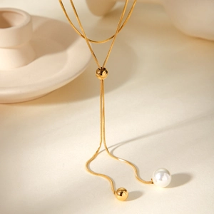 Detail of adjustable gold snake chain with white pearl pendant and sliding metal bead