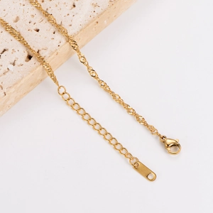 Detail of gold water-wave chain with lobster clasp and adjustable extension on travertine