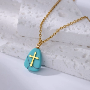 Detailed view of sky blue turquoise cross pendant necklace on a textured white stone base
