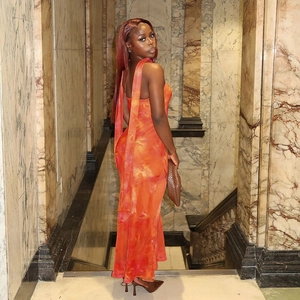 Détail d'une robe tube moulante avec motif tie-dye orange et rubans flottants