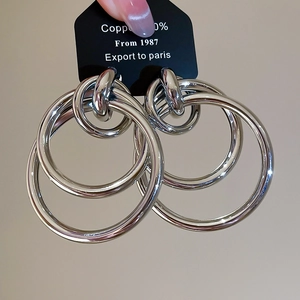 Gros plan de boucles d'oreilles créoles entrelacées en cuivre argenté avec fini poli miroir