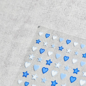 Japanese style blue and white heart star nail art stickers on a grey fabric background