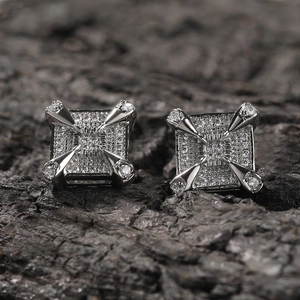 Macro shot of silver dragon claw square stud earrings with zircon on dark wood