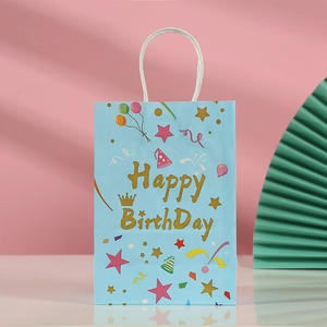 Close-up of blue kraft paper birthday gift bag with golden Happy Birthday text and balloons