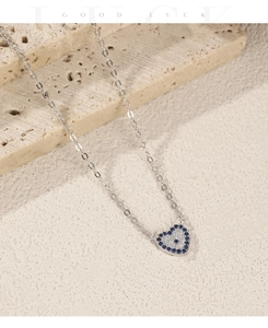 Detailed view of silver heart pendant with blue crystals on light stone background