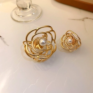 Detailed view of gold metal camellia hair claws with pearls on marble surface