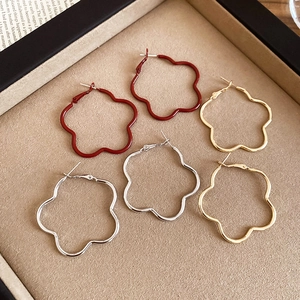 Detailed view of large retro floral hoop earrings in matte red, gold and silver finishes
