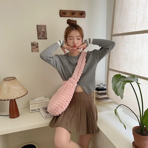 Detailed bubble textured pink crossbody bag styled with a grey cardigan and pleated skirt