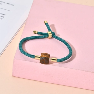 Gros plan détaillé d'un bracelet tressé sarcelle avec pierre naturelle carrée et fermoir doré