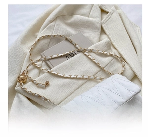 Detail of white quilted crossbody bag with golden chain strap on a chic blazer