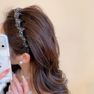 Detail shot of wavy black acrylic headband with sparkling silver rhinestones on hair
