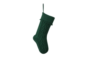 Detail of green knit Christmas stocking with cable pattern and hanging tassels