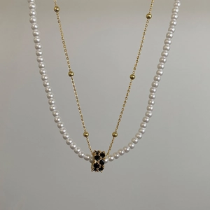 Détail du collier double couche avec perles blanches et pendentif en cristal noir