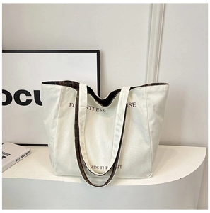 Detailed view of white canvas tote bag with black lettering and plaid lining interior