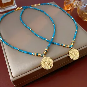 Ethnic style beaded necklace with turquoise beads and gold evil eye coin pendant