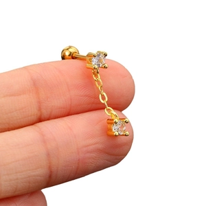 Gold piercing earring with double zircon pendants and chain on a hand for scale