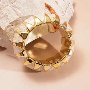 Macro detail of geometric acrylic marble bangle with golden pyramid modules