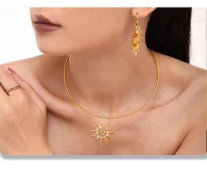 Macro view of gold-plated sun pendant necklace and matching earrings on a model