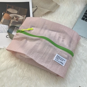 Close-up of pink checkered waterproof travel organizer with vibrant green zipper and puller